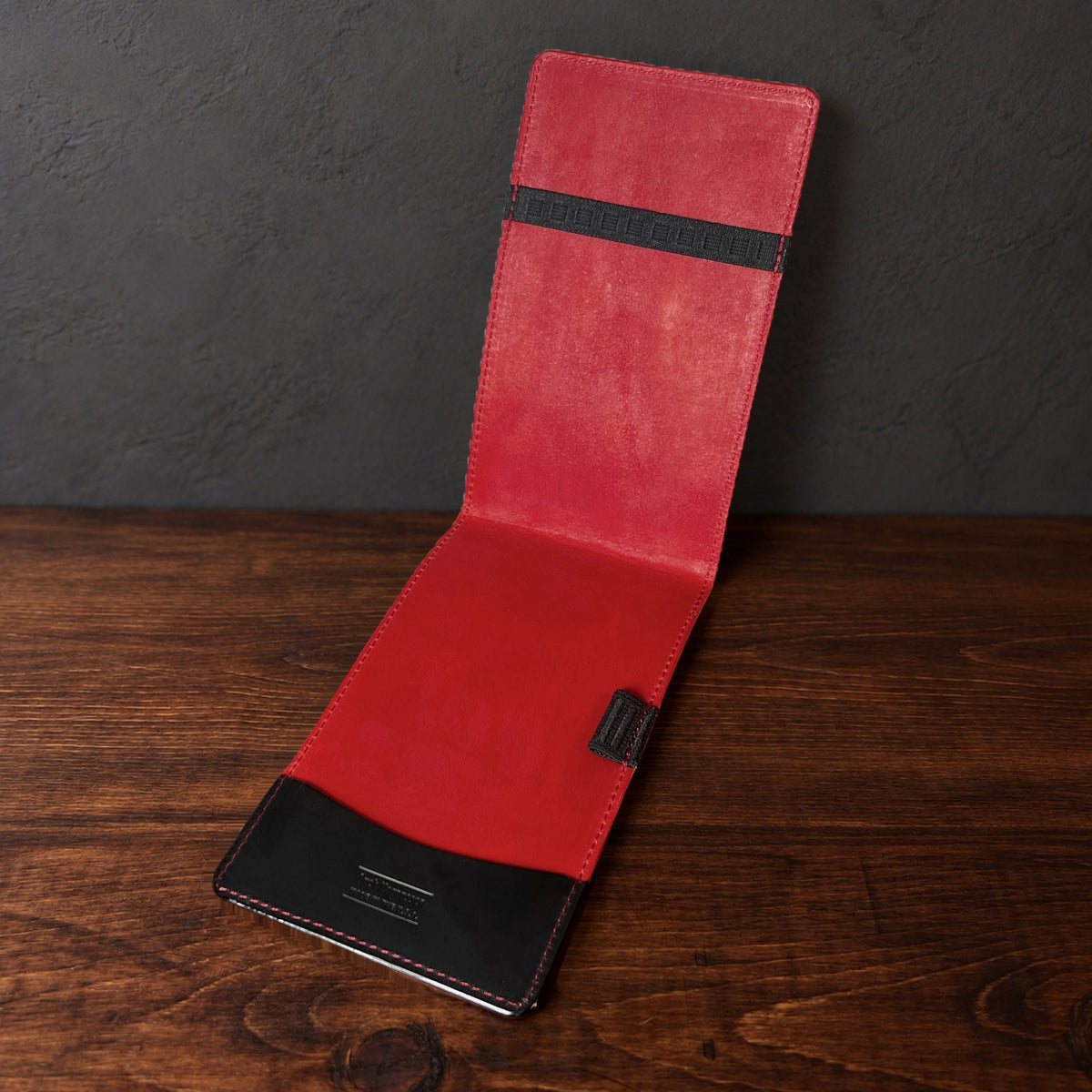 Augusta Pro yardage book cover in Black Waxy standing open, showing the red interior