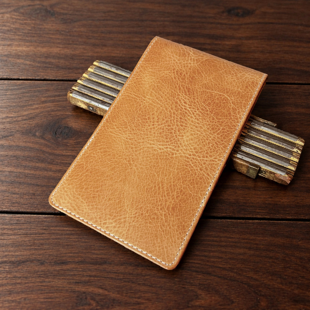 Augusta Pro leather yardage book cover in Natural Waxy with cream thread, closed, on a wood table with pencils