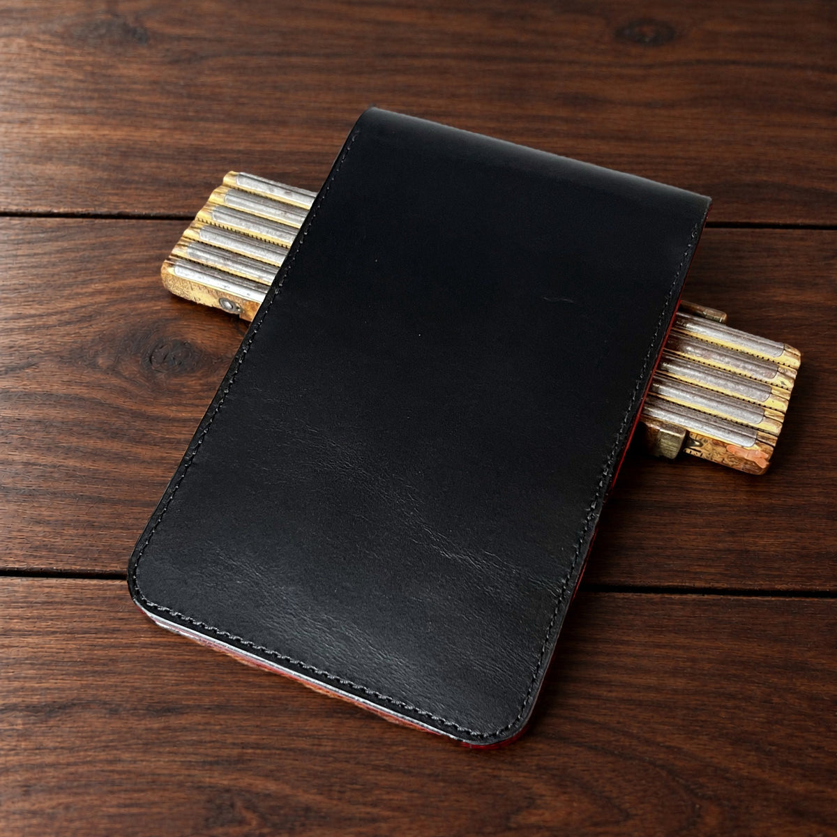 Oakmont Classic leather yardage book cover in Black Buttero with black thread, closed, on a wood table with pencils
