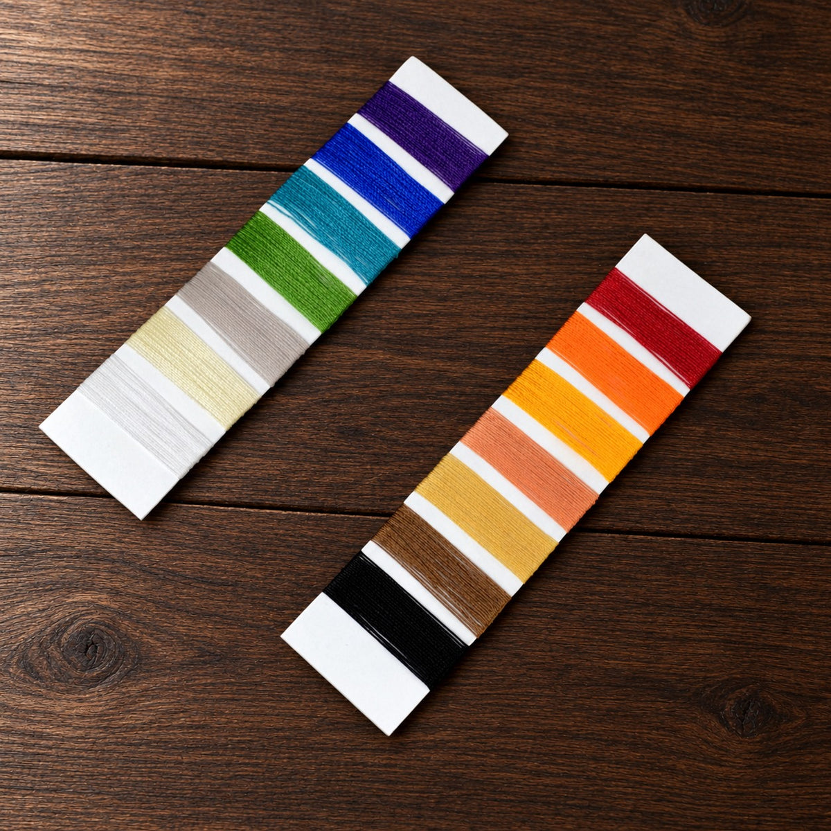 Thread samples in the fourteen thread colors, wound on two white cards on a walnut table
