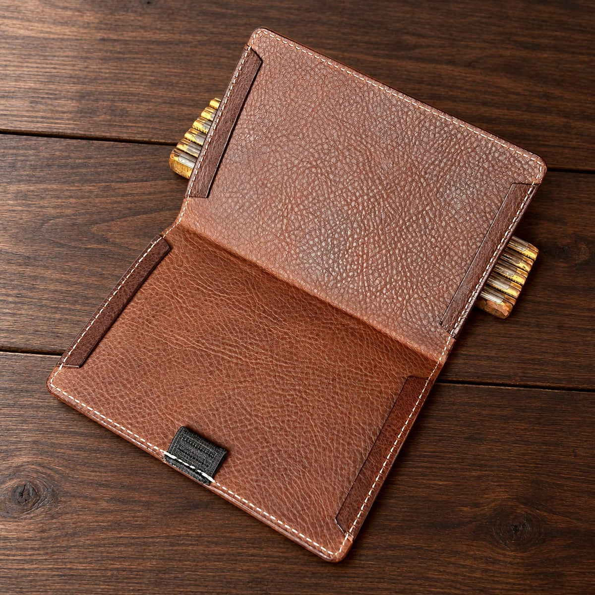 Inside of an open Muirfield scorecard holder on a walnut table: brown pebbled lining with leather panels at the top and bottom of each side and a pencil loop