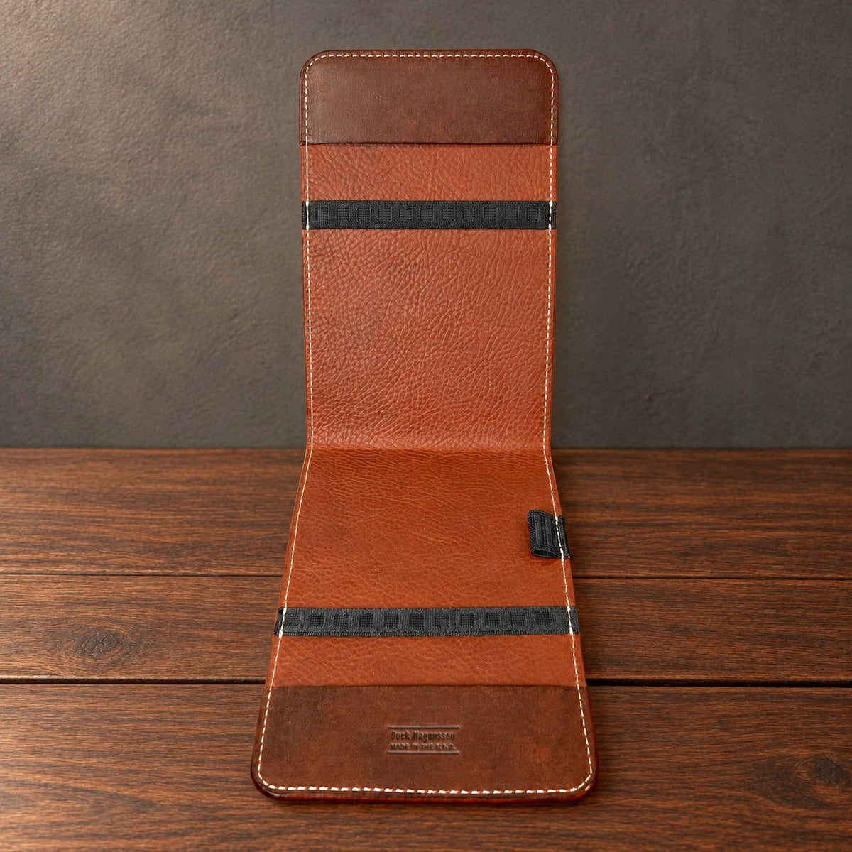 Inside of an open Oakmont yardage book cover standing on a walnut table: elastics at the top and bottom, straight-edge panels and a pencil loop