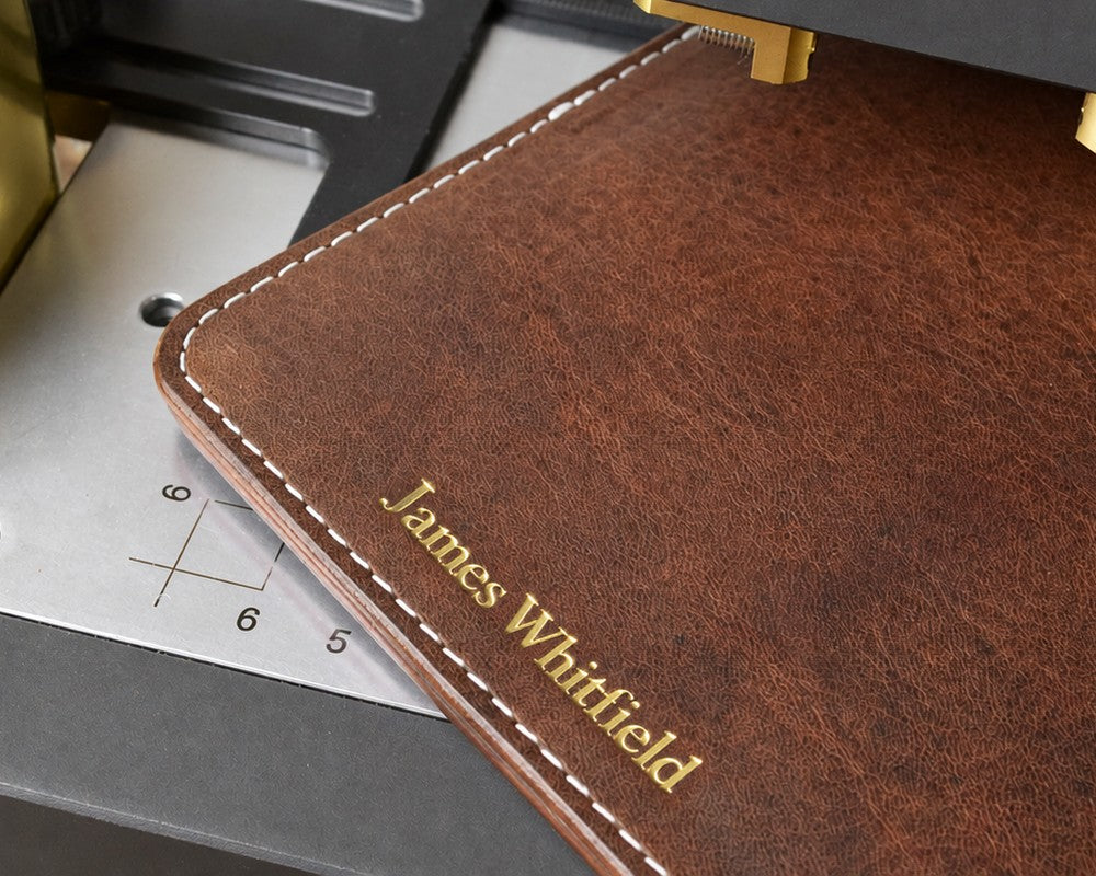 Gold foil name stamped on a brown leather cover in the hot-foil press