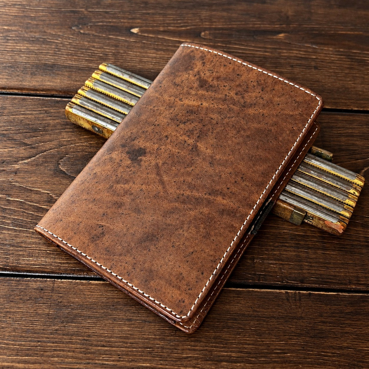 Muirfield leather scorecard holder in brown full-grain leather resting on pencils on a walnut table